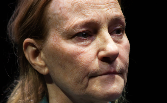 Närbild av medelålders kvinna med ljust hår, blå skjorta, ser åt sidan.