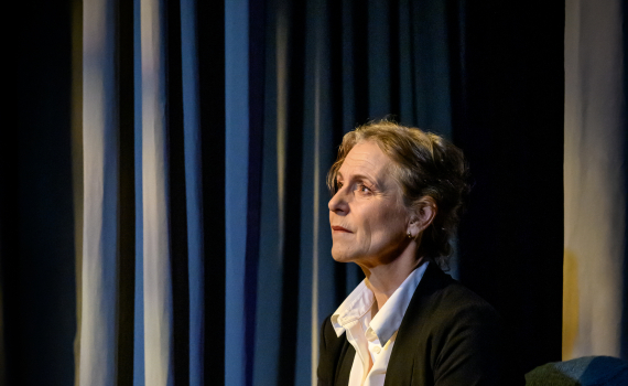 Helen Sjöholm som Margareta Hellstedt sitter blickandes upp mot ljuset.