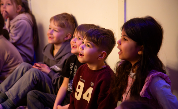 Glad engagerade förskolebarn som tittar på teater.
