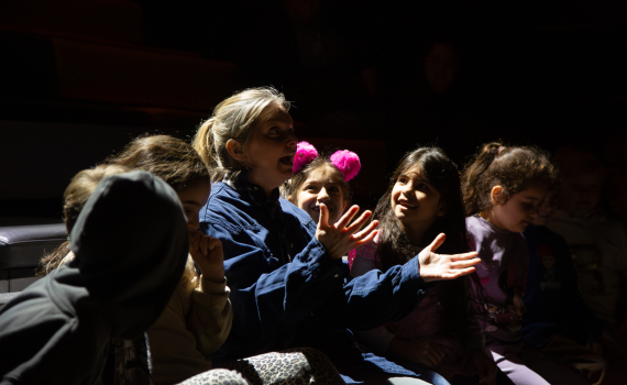 Skådespelare som sitter bland barnen under en föreställning.