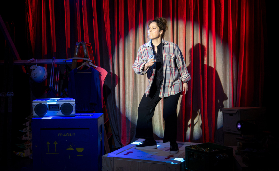 Vanna Rosenberg som står på en flyttkartong och sjunger i ett rött ljus med en spotlight på sig.