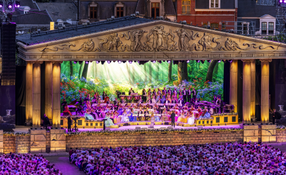 En konsertscen badar i neonljus där en orkester spelar.
