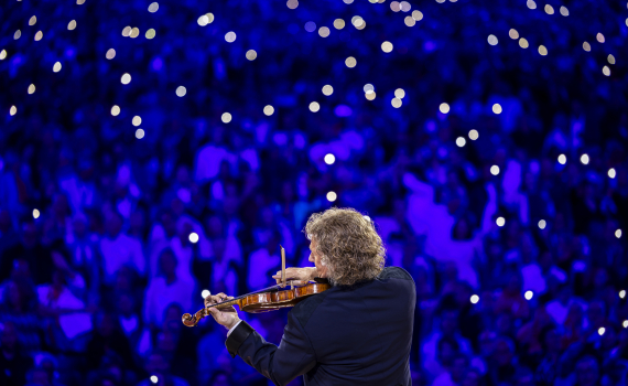 En man i frack spelar violin på en konsertscen.