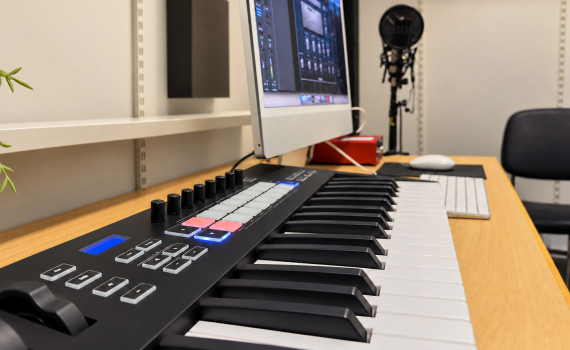 Närbild av ett MIDI-keyboard vid en dator för musikproduktion.
