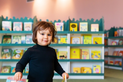 Ett barn framför bokhyllor i bibliotek Rum för Barn.  