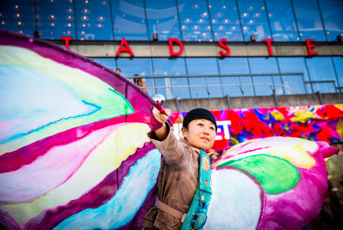 En skådespelare med en dräkt med vingar på står framför Kulturhuset.