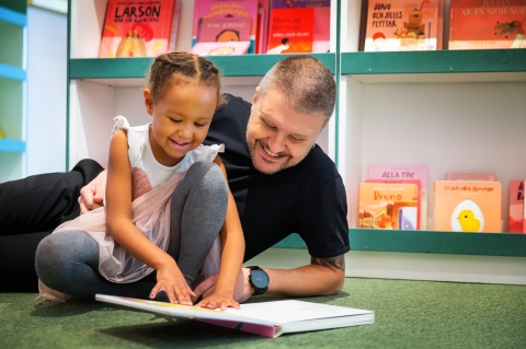 Ett barn och en vuxen läser en bok tillsammans på Rum för Barn.