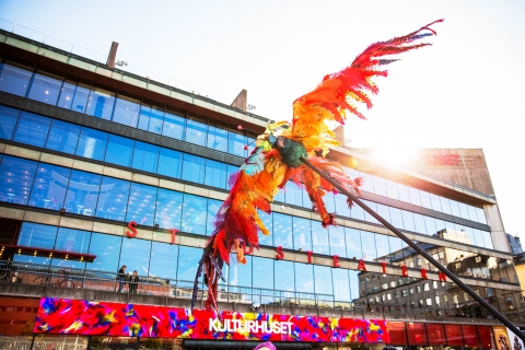 En färgglad fågeldocka hålls upp framför entrén till Kulturhuset.  
