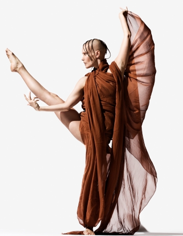 En dansare tar ett danssteg och har ett ben och en arm högt upp i luften.