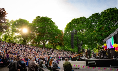 Mycket publik framför scenen i Vitabergsparken en solig sommarkväll