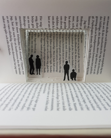 Inuti en bok är ett litet rum skapat där några små figurer befinner sig.