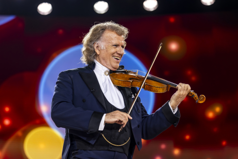 En man i frack spelar violin på en konsertscen.