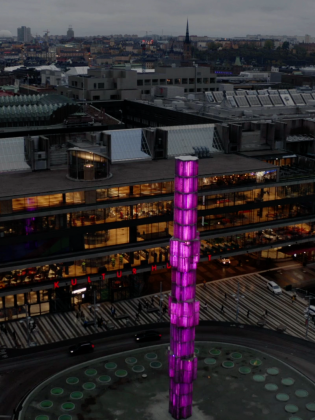 Glasobelisken sedd ovanifrån, utanför Kulturhuset, i lila belysning. 