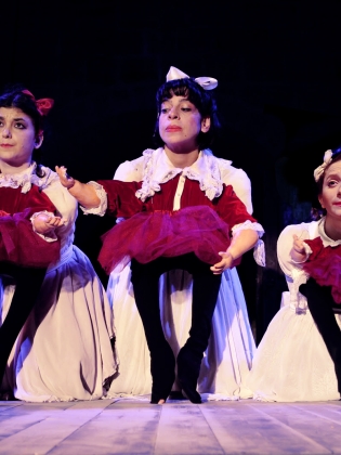 Tre dockskådespelare med tre dockor i röda och vita klänningar. 