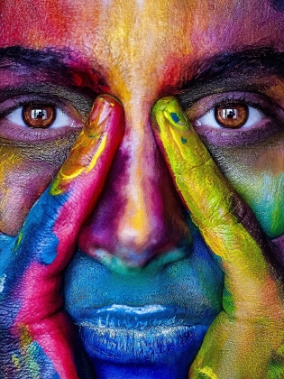Ett ansikte och ett par händer målade i olika färger. 