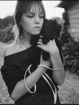 En ung flicka håller i en liten hund
