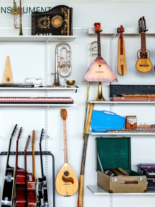 Musikinstrument som hänger på en vägg och ligger på hyllor. 