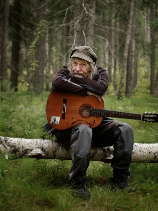 En man med gitarr i skogen