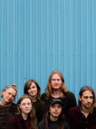 Sex personer framför en blå vägg