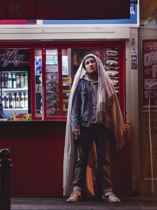 Filmbild av en man som står framför en kiosk