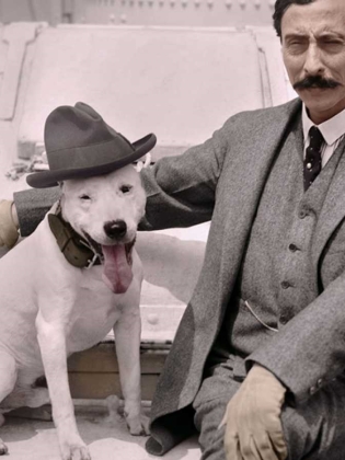 En man sitter bredvid en hund i hatt