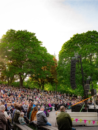 Mycket publik framför scenen i Vitabergsparken en solig sommarkväll