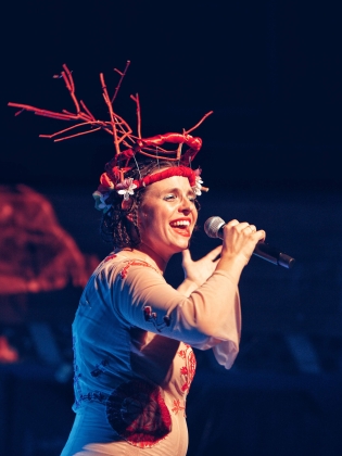 En kvinna som sjunger med folkdräktsinspirerad huvudbonad