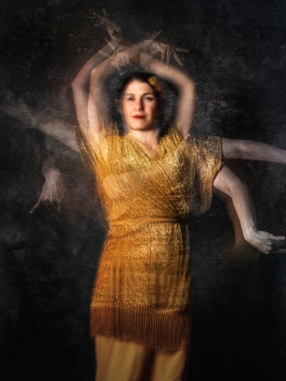 En flamencodansare med flera armar och guldgul klänning