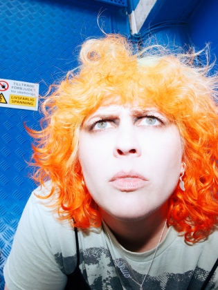 En kvinna med orange hår mot en blå bakgrund
