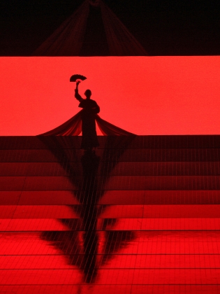 En dansare står på en scen som badar i rött neonljus