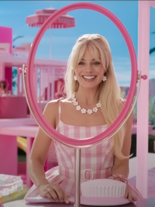 En blond kvinna sitter i ett rosa hus
