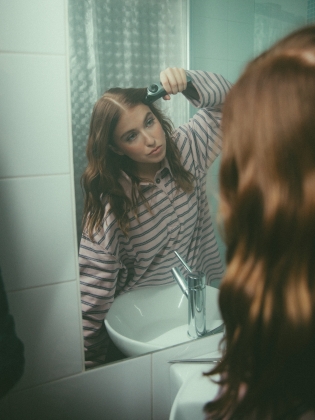 En ung kvinna framför en badrumsspegel
