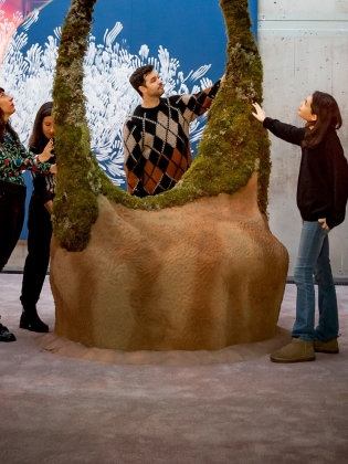 Fyra personer tittar och känner på en stor skulptur. 