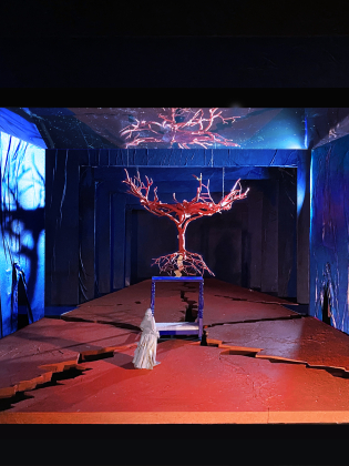 En operascen är fantasifullt koreograferat med ett stort rött träd.