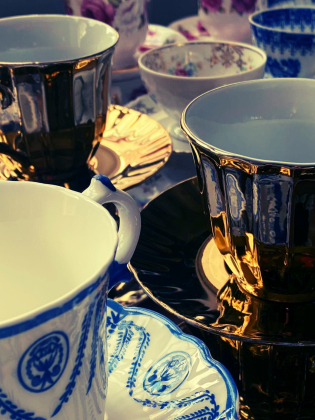 Flera porslinskopp med fat i olika mönster och färger, inklusive guld, blåvitt och blommigt.