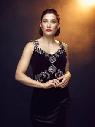 Julia Küster i en svartglittrig klänning upplyst av ett varmt gult ljus.