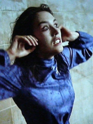 En kvinna i blå klänning gör en hysterisk grimas.