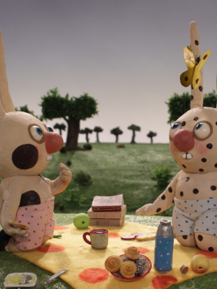 Två leranimerade kaniner har picknic på en äng.