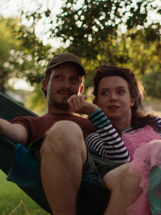 Ett par sitter i en hängmatta i en solig park.