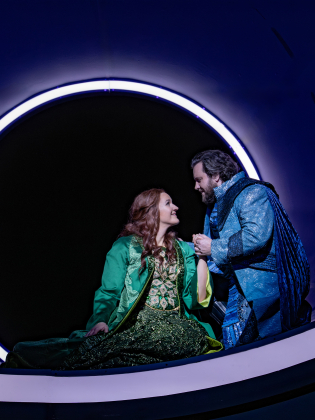 Ett par håller om varandra på en scen med lila ljus.