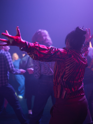 Människor i ett mörkt rum som dansar i färgglada kläder