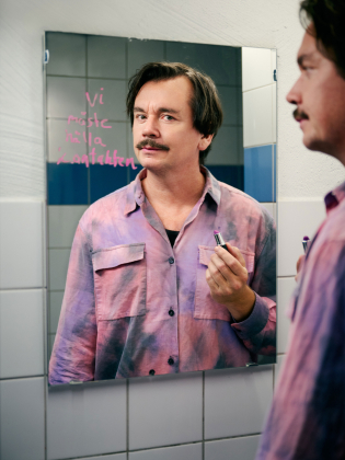 En man i rosa skjorta framför en spegel