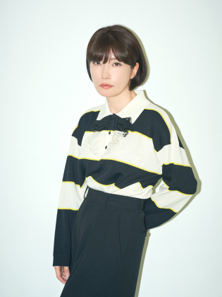 Mieko Kawakami står mot en ljus bakgrund i ett minimalistiskt porträtt med tydliga kontraster och ett lugnt, fokuserat uttryck.