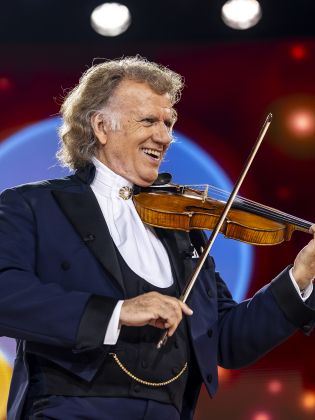 En man i frack spelar violin på en konsertscen.