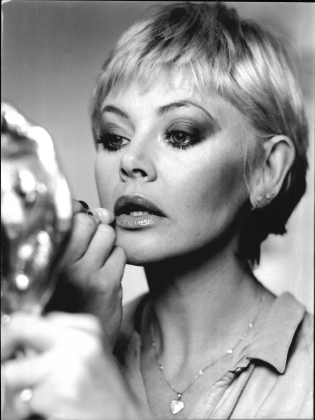 Britt Ekland som målar sina läppar med en handspegel framför sig