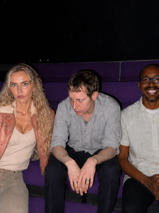 tre personer sitter i en teater