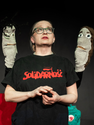 Gertrud Larsson med två strumpdockor bakom sig.
