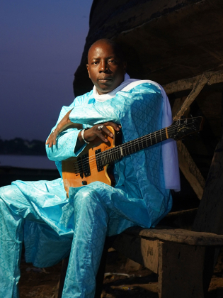 En man i turkosa kläder med en gitarr